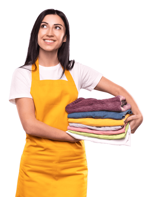 A smiling woman with long dark hair wearing a yellow apron holds a neatly folded stack of laundry. She glances up to her left, standing against a white background, satisfied with the quality and prices of her clean clothes.